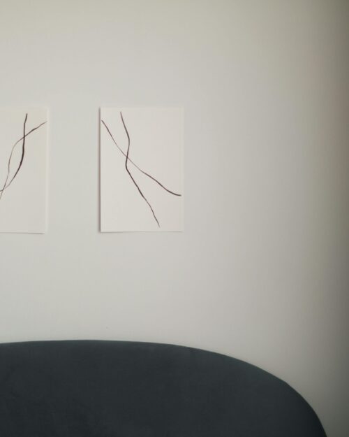 Abstract linear wall art in a minimalist modern living room with soft lighting.